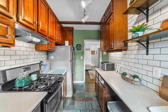 kitchen with stone tile floors, light countertops, under cabinet range hood, stainless steel range with gas cooktop, and open shelves