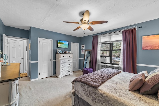 bedroom with radiator, light carpet, ceiling fan, a textured ceiling, and baseboards