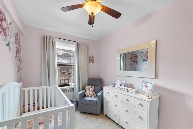 bedroom featuring light carpet, ceiling fan, a crib, and radiator heating unit