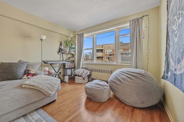 sitting room featuring wood-type flooring, radiator, and cooling unit