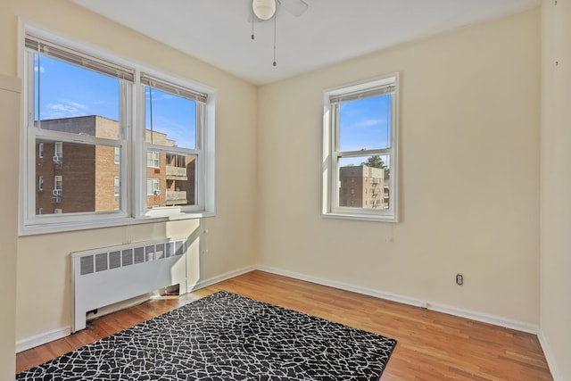 spare room with ceiling fan, radiator heating unit, and wood-type flooring