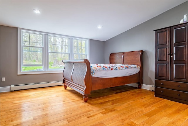 bedroom featuring light hardwood / wood-style flooring, vaulted ceiling, and baseboard heating