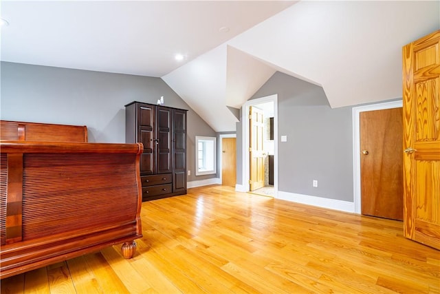 unfurnished bedroom with vaulted ceiling and light wood-type flooring