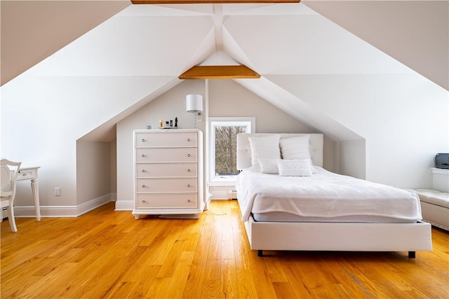 bedroom featuring vaulted ceiling with beams and light hardwood / wood-style flooring