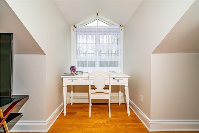 home office with lofted ceiling, a baseboard heating unit, and light wood-type flooring