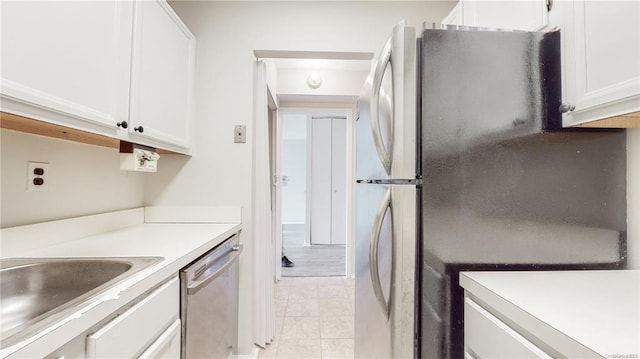 kitchen with sink, light tile patterned floors, stainless steel appliances, and white cabinets