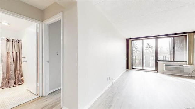 interior space with light hardwood / wood-style floors and a wall unit AC