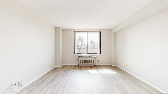 unfurnished room featuring radiator and light wood-type flooring