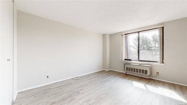 empty room featuring radiator heating unit and light hardwood / wood-style floors