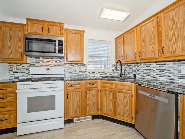 kitchen with stainless steel appliances, ornamental molding, sink, and backsplash