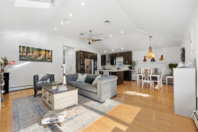 living room featuring light hardwood / wood-style flooring, a baseboard heating unit, and vaulted ceiling