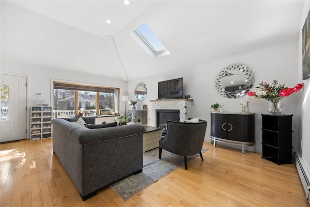 living room featuring a baseboard radiator, a fireplace, a skylight, and light hardwood / wood-style floors