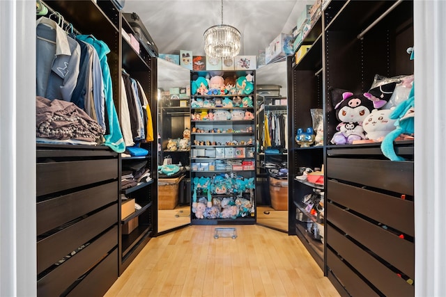 spacious closet featuring a chandelier and light wood-type flooring