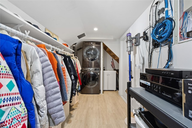 walk in closet featuring light wood-type flooring, vaulted ceiling, and stacked washing maching and dryer