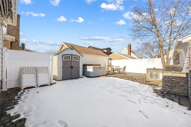 yard covered in snow featuring exterior kitchen, a storage unit, and a patio area