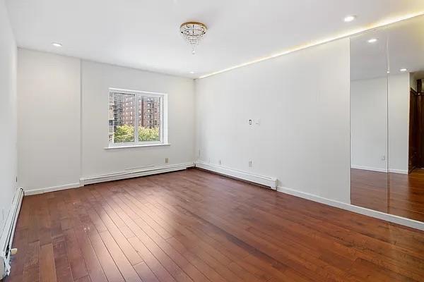 unfurnished room with dark hardwood / wood-style flooring and baseboard heating