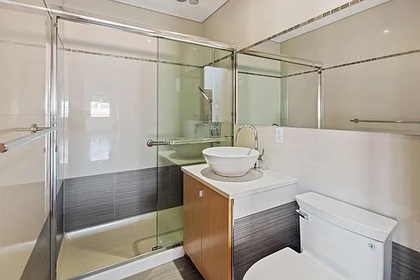 bathroom with vanity, a shower with door, and toilet