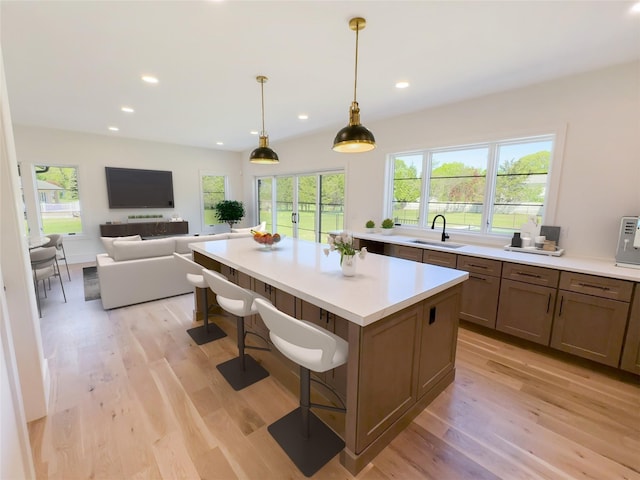 2045 Willow Dr, East Marion, NY 11939 - kitchen with light wood finished floors, a sink, light countertops, a center island, and a kitchen bar