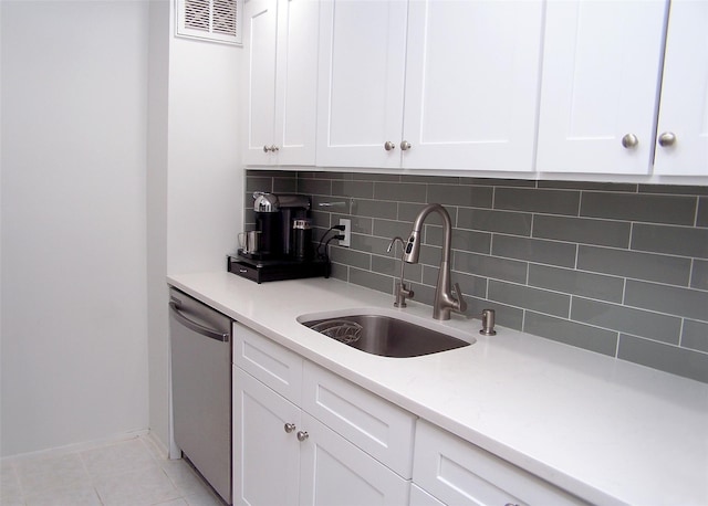 kitchen with light tile patterned flooring, sink, white cabinetry, tasteful backsplash, and dishwasher