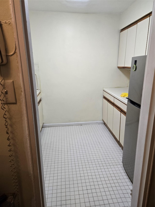 kitchen with stainless steel refrigerator and white cabinets