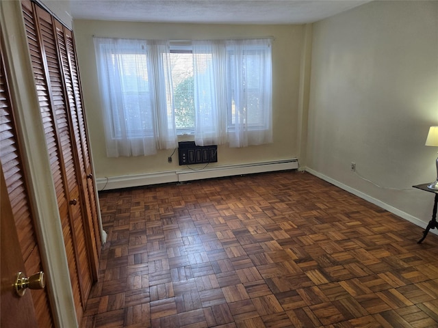 unfurnished room featuring baseboard heating and dark parquet floors