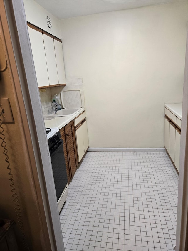 kitchen featuring range with gas stovetop, tasteful backsplash, white cabinetry, sink, and light tile patterned floors