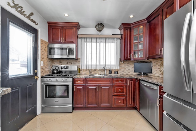 kitchen featuring light tile patterned flooring, sink, decorative backsplash, light stone counters, and stainless steel appliances