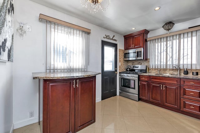 kitchen featuring light tile patterned flooring, sink, appliances with stainless steel finishes, light stone countertops, and backsplash