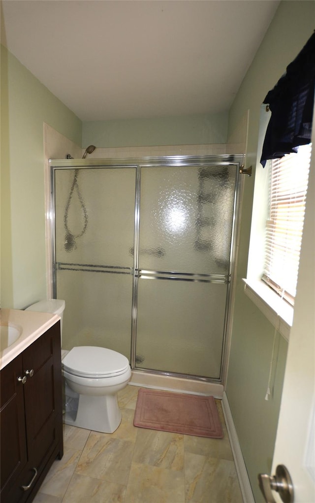 bathroom featuring vanity, a shower with door, and toilet