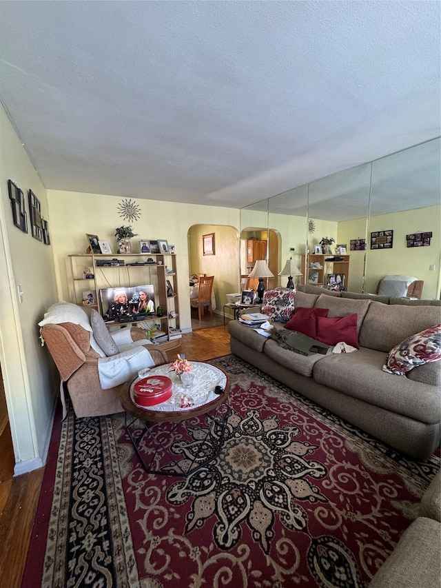 living area featuring arched walkways, a textured ceiling, and wood finished floors