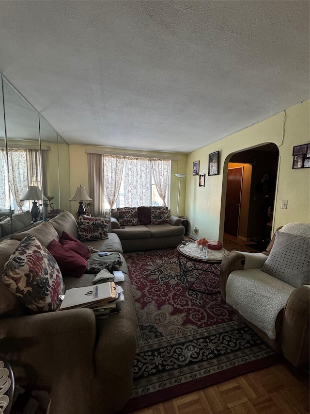 living room featuring arched walkways and a textured ceiling