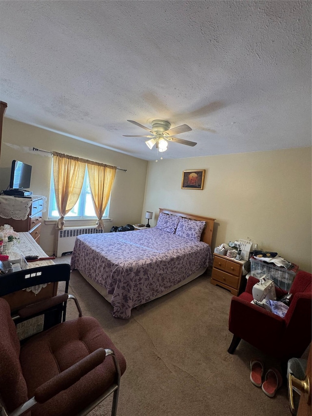 carpeted bedroom with a ceiling fan, radiator heating unit, and a textured ceiling