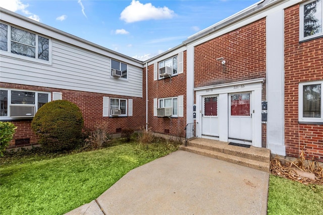 property entrance with crawl space, cooling unit, and brick siding