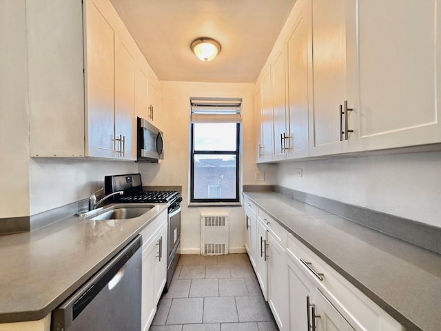 kitchen featuring white cabinetry, sink, radiator heating unit, and appliances with stainless steel finishes