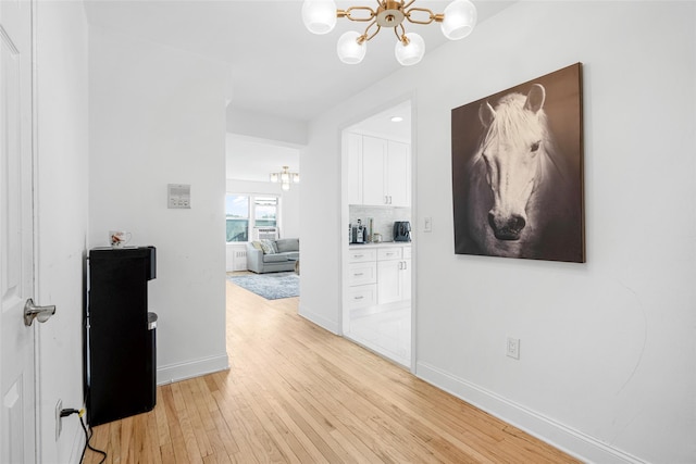 corridor featuring an inviting chandelier and light hardwood / wood-style flooring