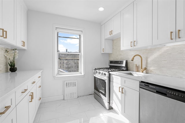 kitchen with appliances with stainless steel finishes, light stone countertops, sink, and white cabinets