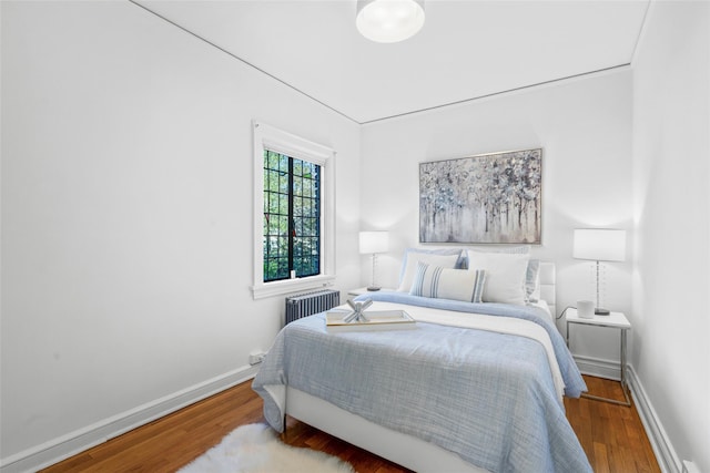 bedroom featuring baseboards, wood finished floors, and radiator