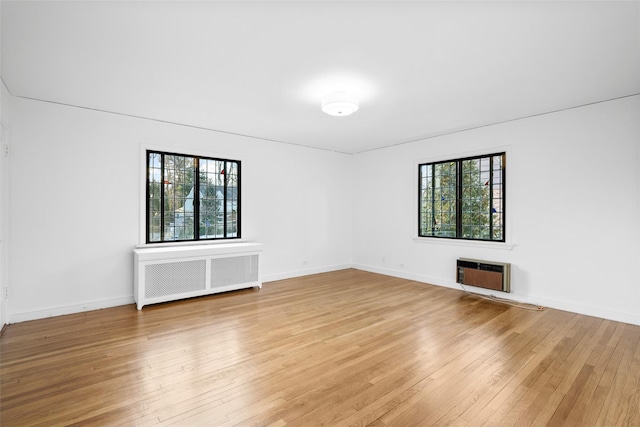 empty room with radiator, heating unit, baseboards, and wood finished floors