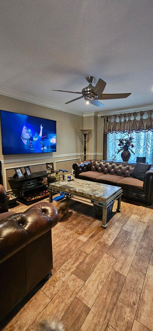 living room with ceiling fan, crown molding, a textured ceiling, and light wood-type flooring