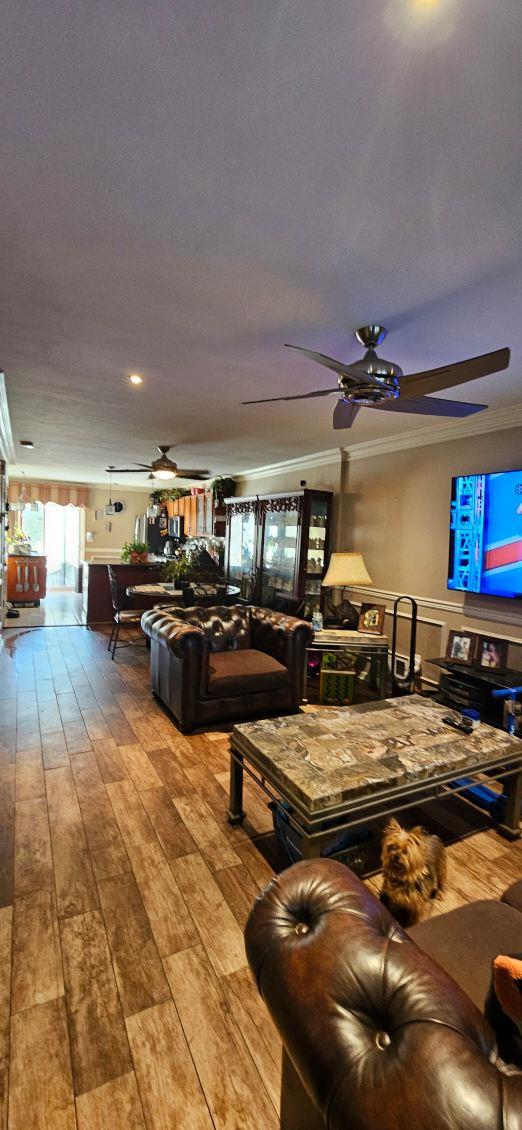 living room with crown molding, hardwood / wood-style floors, and ceiling fan