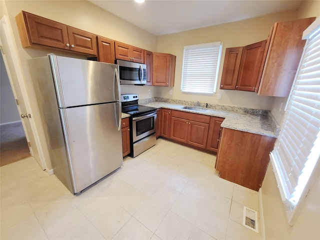 kitchen with light stone counters, sink, and appliances with stainless steel finishes