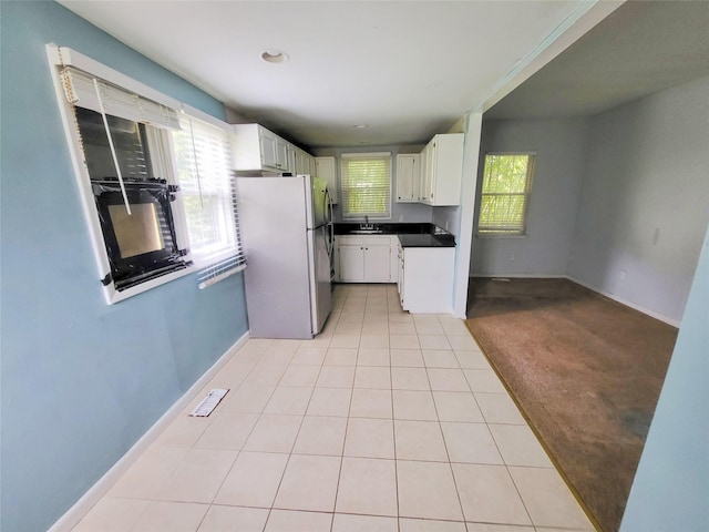 kitchen with white cabinetry, stainless steel fridge, sink, and light carpet