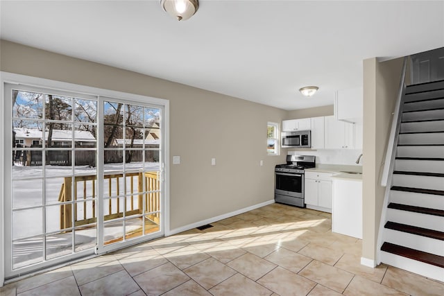 kitchen with white cabinetry, appliances with stainless steel finishes, sink, and light tile patterned floors