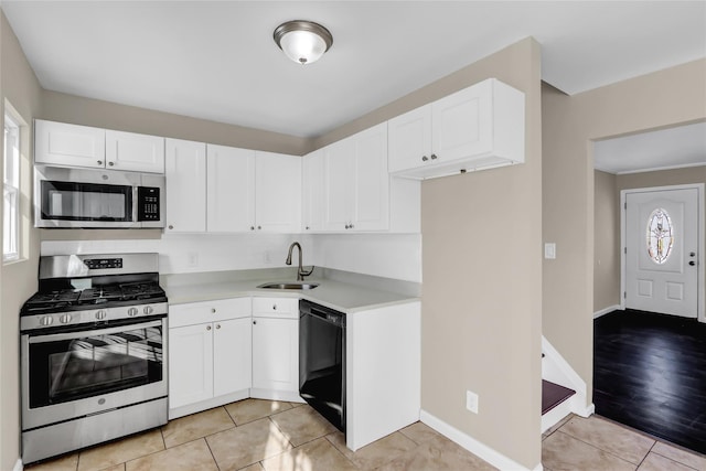 kitchen with light tile patterned floors, appliances with stainless steel finishes, sink, and white cabinets