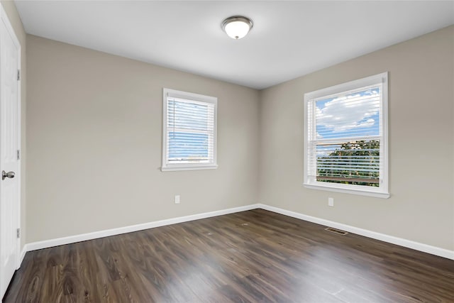 unfurnished room with dark wood-type flooring