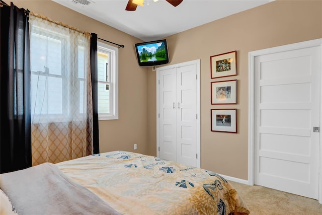 bedroom featuring light carpet, ceiling fan, and a closet