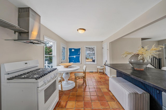 kitchen featuring exhaust hood, white range with gas stovetop, and light tile patterned floors