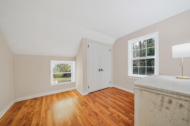 bonus room with vaulted ceiling, a healthy amount of sunlight, and light wood-type flooring