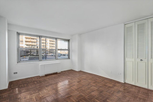 empty room featuring radiator heating unit and dark parquet floors