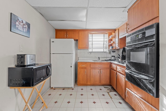 kitchen with a drop ceiling, sink, and white refrigerator